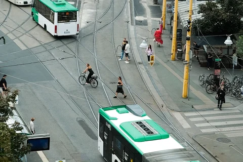 Aerial view of city intersection with tram, bikes, and pedestrians.